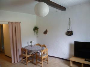 ein Esszimmer mit einem Tisch und Stühlen sowie einem TV in der Unterkunft Une vue sur la Baume in Sisteron