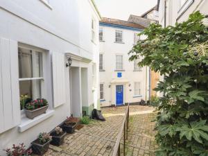 eine schmale Straße mit weißen Häusern und einer blauen Tür in der Unterkunft Grants Cottage in Dartmouth