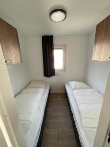 twee bedden in een kleine kamer met een raam bij Zee en duin in IJmuiden