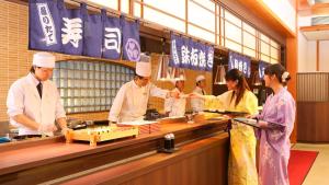 um grupo de chefs preparando comida em uma cozinha em Ooedo Onsen Monogatari Higashiyama Grand Hotel em Aizuwakamatsu
