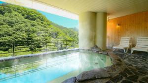a pool in a house with a view of the mountains at Ooedo Onsen Monogatari Higashiyama Grand Hotel in Aizuwakamatsu