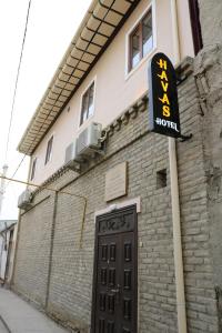 a sign for a hotel next to a building at HAVAS Guest House in Bukhara