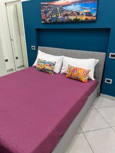 1 cama con sábanas y almohadas moradas en una habitación en Martina House, en Afragola