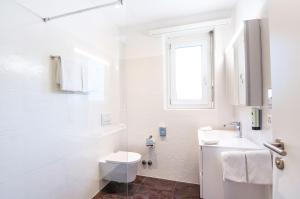 a white bathroom with a toilet and a sink at Hotel Polo in Ascona