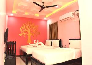two beds in a room with a tree on the wall at Temple stay - Uma Residency and Guest House in Mayiladuthurai