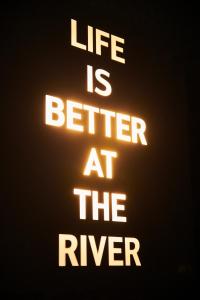 a neon sign that says life is better at the river at Designhotel ÜberFluss in Bremen