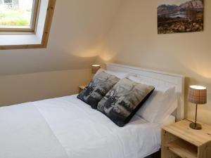 a bedroom with a white bed with two pillows on it at Elmbank in Lochcarron