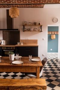 a kitchen with a wooden table with plates on it at Gîte Le carré 1869 in Landas