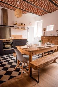 a kitchen with a wooden table with chairs and a kitchen with at Gîte Le carré 1869 in Landas