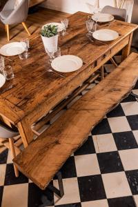 a wooden table with plates and glasses on it at Gîte Le carré 1869 in Landas