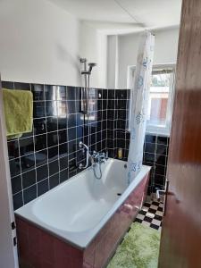 uma casa de banho com banheira e azulejos pretos em Ferienwohnung ADAM im Haus Heidi em Höchenschwand