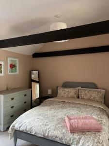 a bedroom with a large bed with a pink pillow on it at The Barn in Saxmundham