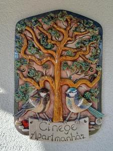 dos pájaros sentados bajo un árbol con una señal en Cinege Apartman en Felsőpáhok