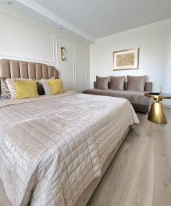 - une chambre avec un grand lit et un canapé dans l'établissement Vanilės apartamentai, à Klaipėda