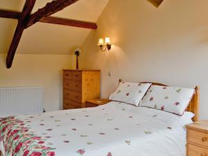 a bedroom with a bed and a wooden dresser at Nightingales in Kentisbeare