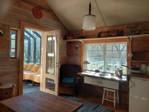 eine Küche mit einem Schreibtisch und Fenstern in einer Hütte in der Unterkunft Puise saunahouse and outdoor kitchen at Matsalu Nature Park in Puise