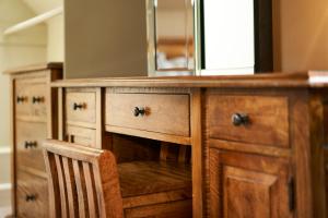 a wooden dresser with a mirror and a wooden chair at Ulbster Arms Hotel near Thurso in Halkirk