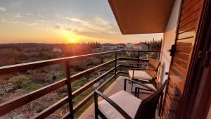 een balkon met stoelen en de zonsondergang op de achtergrond bij Le Petit in Čilipi