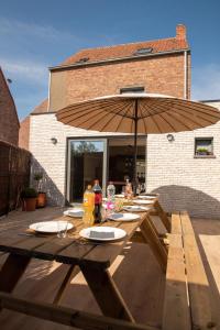 a wooden picnic table with an umbrella on a patio at Vakantiewoning Dorp-28 in Hollebeke