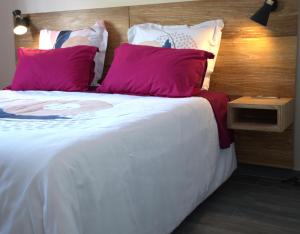 a large bed with two pink pillows on it at Villa Le Jacaranda in Salazie