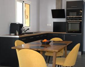 a kitchen with a wooden table and yellow chairs at Villa Le Jacaranda in Salazie