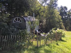una piccola casa in un cortile con una recinzione di historischer Zirkuswagen inmitten der Natur a Fischach