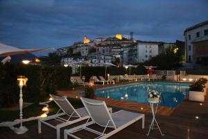 basen z krzesłami i budynkiem w obiekcie Albergo Ristorante Cavaliere w mieście Caselle in Pittari