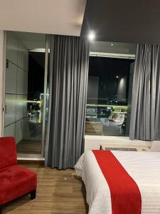 - une chambre avec un lit et une chaise rouge dans l'établissement Zújmú Business Boutique Hotel, à Aguascalientes