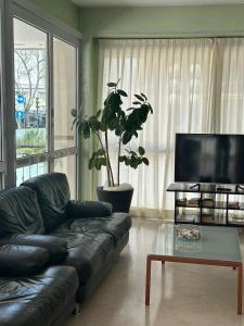 a living room with a black leather couch and a tv at Hotel Ambra in Rimini