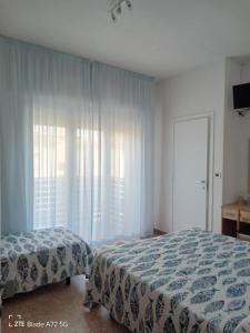 a bedroom with two beds and a large window at Ninfea rooms in Cervia