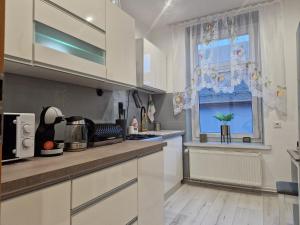 a kitchen with white cabinets and a window at Apartament Przy Rynku in Lewin Kłodzki