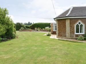 a yard of a brick house with a large lawn at Gamekeepers Cottage in Middleton