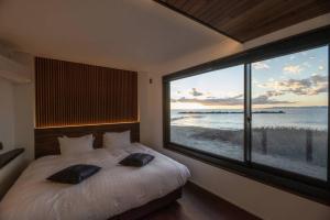 a bedroom with a large window with a view of the ocean at BLUE ARK in Izu