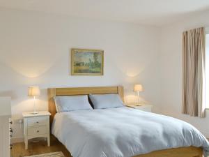 a bedroom with a white bed with two night stands and two lamps at Bayview Cottage in Plockton