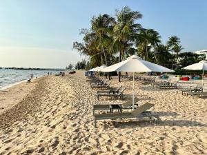 a beach with chairs and umbrellas and the ocean at 8BR West coast Phu Quoc townhouse by beach and shared swimming pools in Phú Quốc