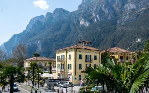 a yellow building with a mountain in the background at Riva Central Apartment - Free Parking in Riva del Garda