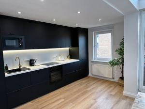 een keuken met zwarte kasten en een houten vloer bij 3 Bedroom/3 Bathroom Large Flat Near OVO Hydro in Glasgow