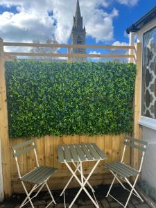 two chairs and a table in front of a hedge at St Annex, Boutique Holiday Apartment for 2 people in Torquay - with Private HOT TUB! in Torquay