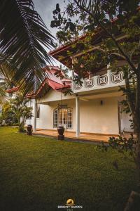 a white house with a green lawn in front of it at Bright Waves Villa in Bentota