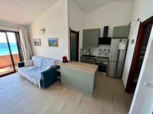 a living room with a kitchen with a couch and a refrigerator at Pinus Village Apartments 4 vista mare in Forte Village