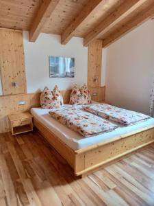 ein Schlafzimmer mit einem großen Bett in einem Zimmer mit Holzböden in der Unterkunft Pferdehof Ansteingut in Schluderns
