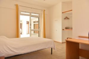 a white bedroom with a bed and a window at Residencial Che Guevara Bed & Breakfast in Mindelo