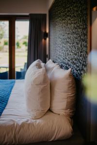 Bett mit weißen Kissen in einem Hotelzimmer in der Unterkunft Motel-Restaurant-Grand Cafe de Caisson in Kapelle