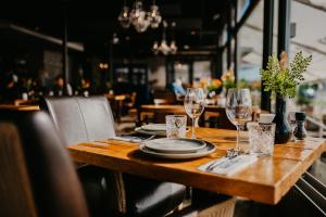 a wooden table with plates and wine glasses on it at Motel-Restaurant-Grand Cafe de Caisson in Kapelle +20 photos