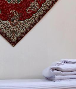 a rug hanging on a wall next to a pile of towels at Donish Hotel in Bukhara
