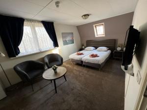 a hotel room with two beds and a table and chairs at Hotel Huys ter Schelde in Koudekerke