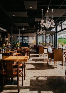 een restaurant met houten tafels en stoelen en kroonluchters bij Motel-Restaurant-Grand Cafe de Caisson in Kapelle