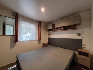 a small bedroom with a bed and a window at MOBIL HOME 68 JARDINS ATLANTIQUE in Saint-Jean-de-Monts