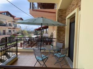 a patio with a table and chairs and an umbrella at ZeusPlace House Marousso in Litochoro