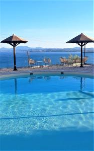 a swimming pool with chairs and umbrellas next to the water at Stefanosplace ApartHotel Sea View in Barbati